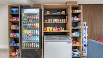 Une chambre d’hôtel équipée d’un mini-bar et de présentoirs remplis de collations, de boissons et d’articles de toilette.
