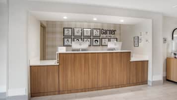 A reception area with a wooden counter, framed artwork on the wall, and a sign that reads "Garner BY IHG".