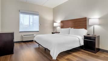 Hotellihuone, jossa on suuri sänky, kaksi yöpöytää valaisimineen, ikkuna, jossa on sälekaihtimet, ja sisäänrakennettu lämmitin.