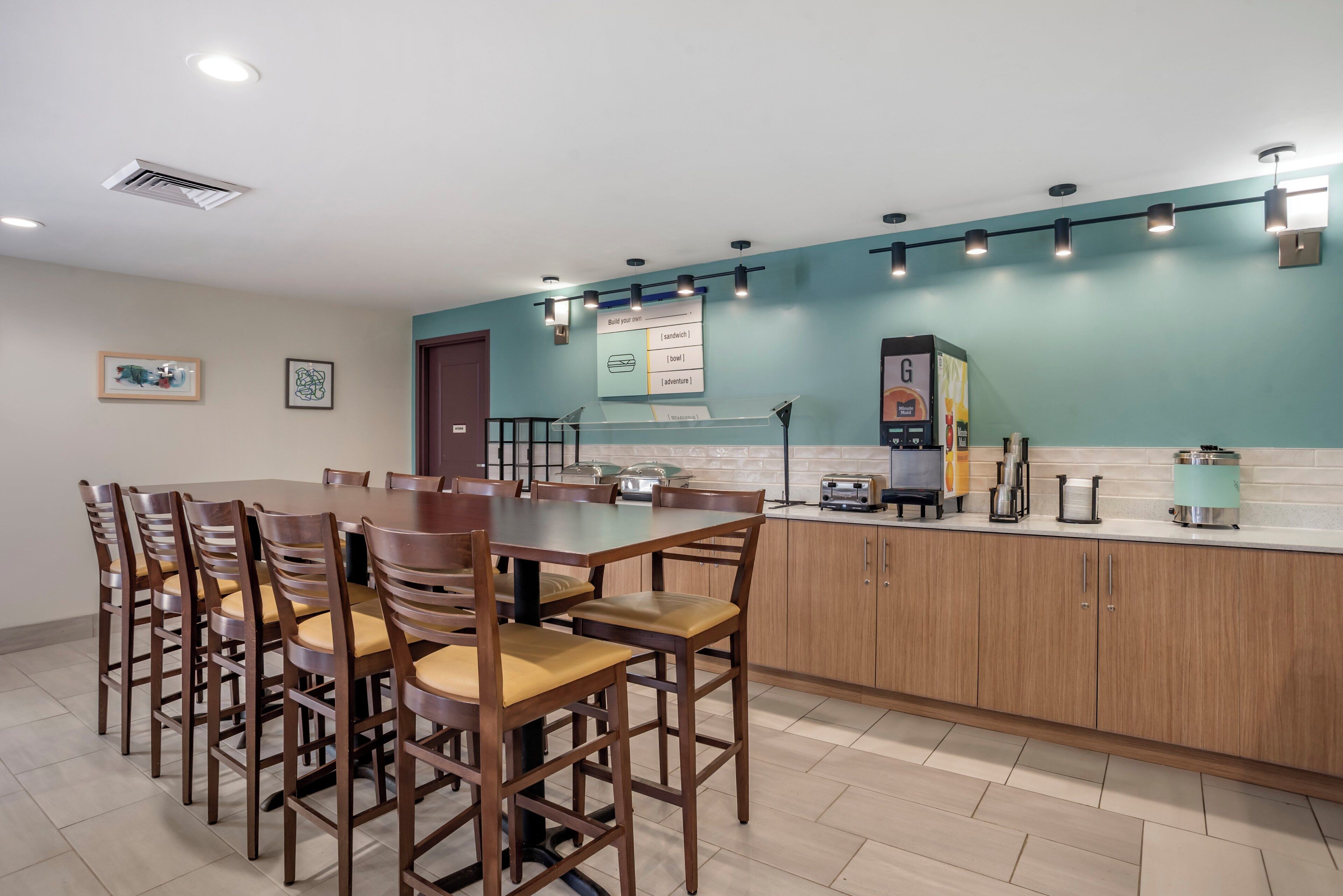 A modern kitchen with a dining area, featuring a large island, wooden cabinets, and a tiled floor.