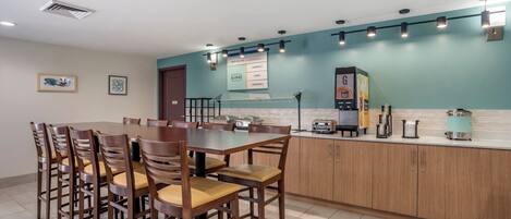 A modern kitchen with a dining area, featuring a large island, wooden cabinets, and a tiled floor.