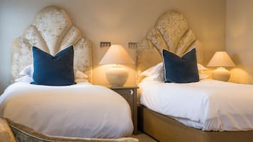 Habitación de hotel con dos camas, cada una con cabecera, lámparas de noche y almohadas.
