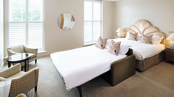 Ein Hotelzimmer mit einem großen Bett, zwei Nachttischen, einem runden Spiegel, einem kleinen runden Tisch und zwei Stühlen.