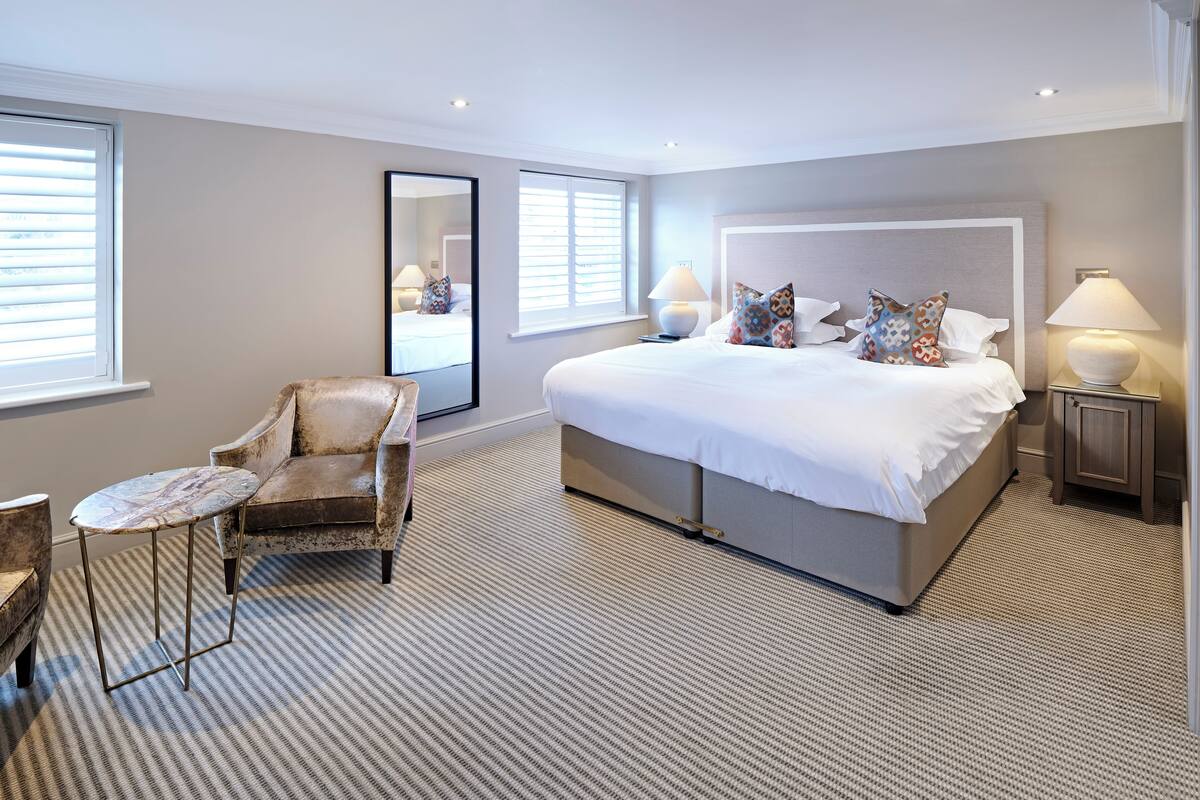 A spacious bedroom with a large bed, a chair, and a small table.