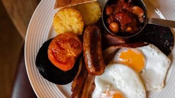 Une assiette de nourriture pour le petit-déjeuner comprenant des toasts, des haricots, des saucisses, des œufs et des tomates.