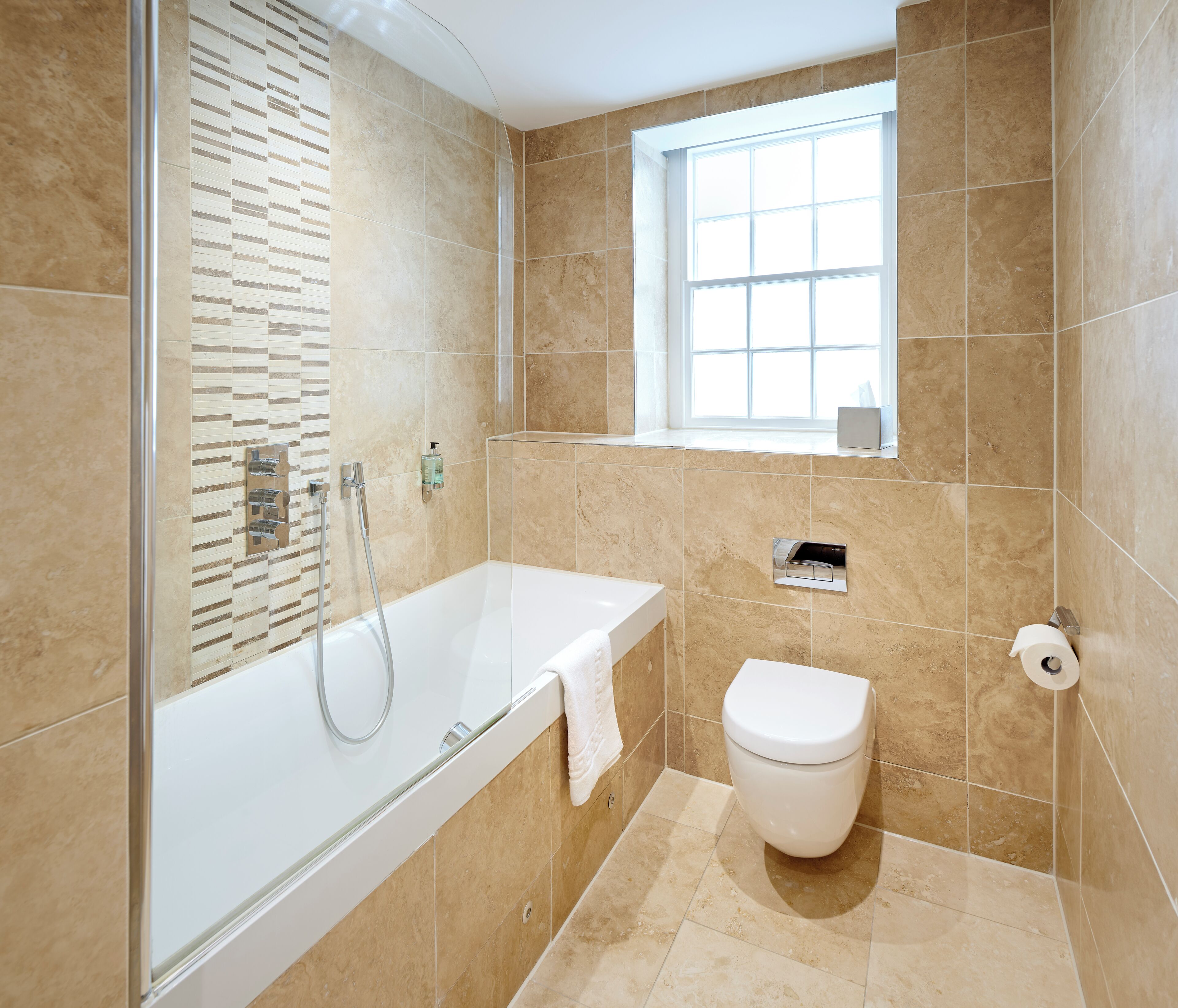 A modern bathroom with a glass-enclosed shower, a white bathtub, and a toilet.