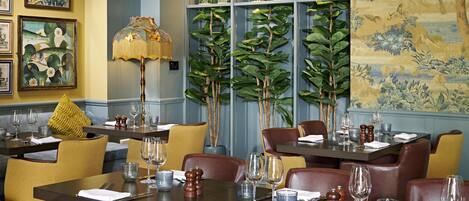 A restaurant with tables set for dining, chairs, and a decorative lamp.