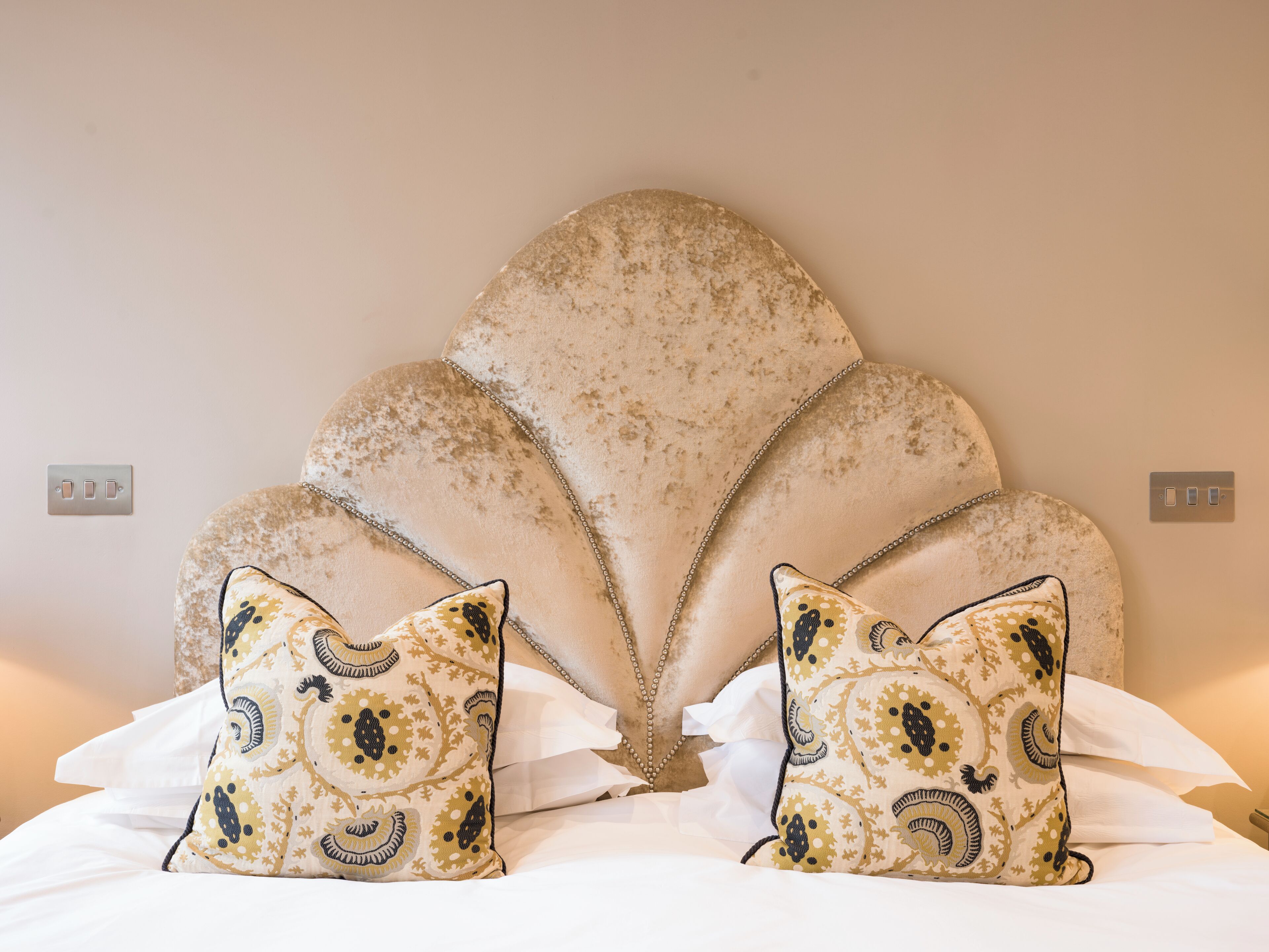 A bed with a unique scalloped headboard and patterned pillows.