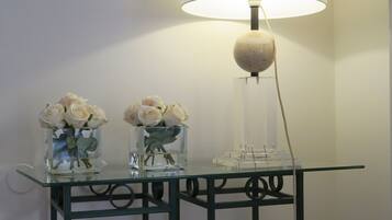 Een glazen tafel met twee vazen witte rozen en een vloerlamp.