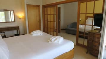 Habitación de hotel con una cama grande, un aparador de madera, un escritorio, una silla y una televisión.