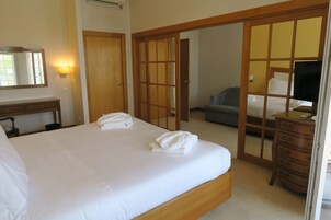 Habitación de hotel con una cama grande, un aparador de madera, un escritorio, una silla y una televisión.
