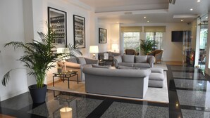 A modern living room with a grey sofa, a coffee table, and a potted plant. - Hotel Toural (Guimarães)