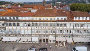 A multi-story hotel with a central entrance, ground-floor shops, and a parking area. - Hotel Toural (Guimarães)