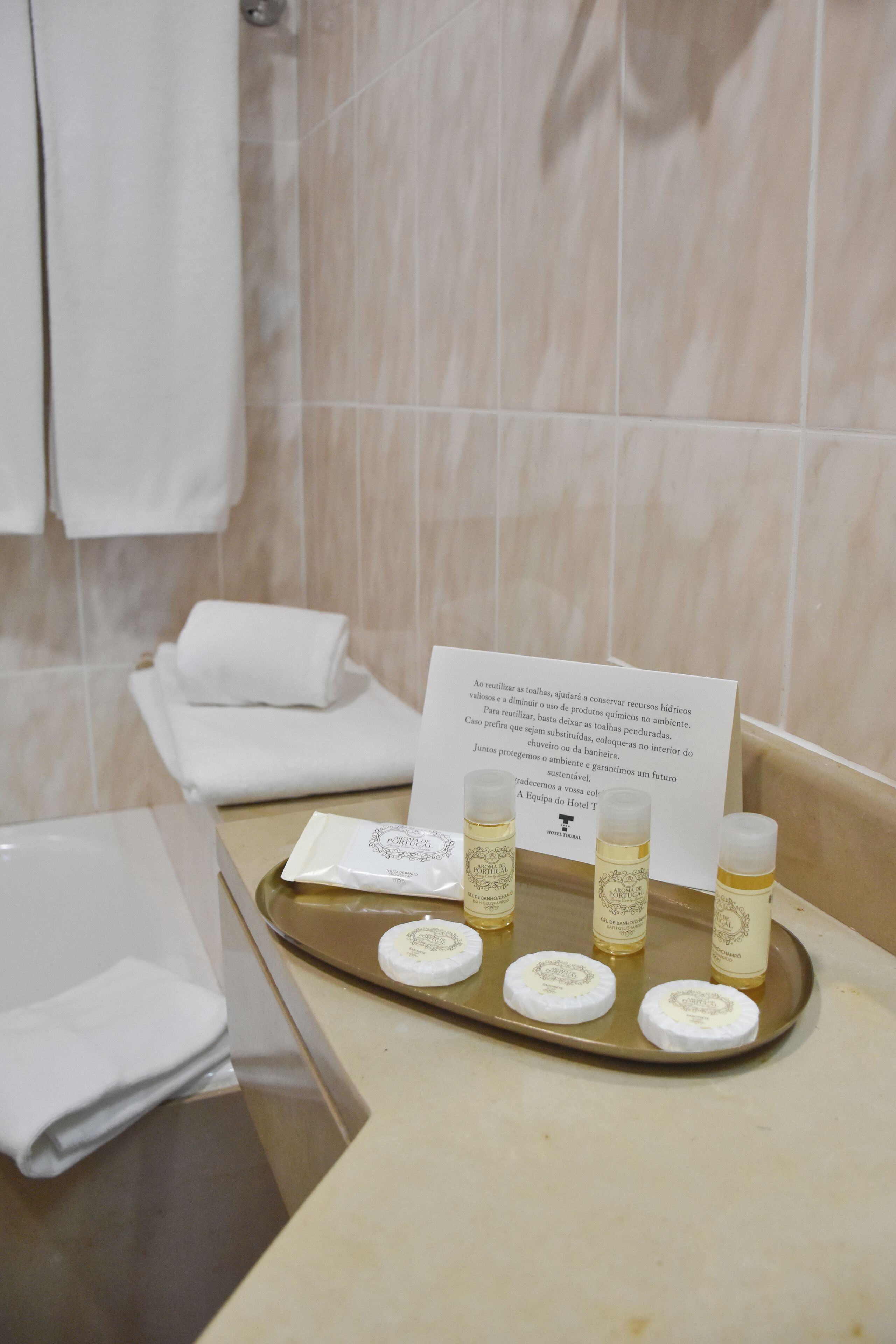 Ein Badezimmer mit einer beige gefärbten Ablagefläche, einer Tablett mit Toilettenartikeln und einem Schild mit Text.