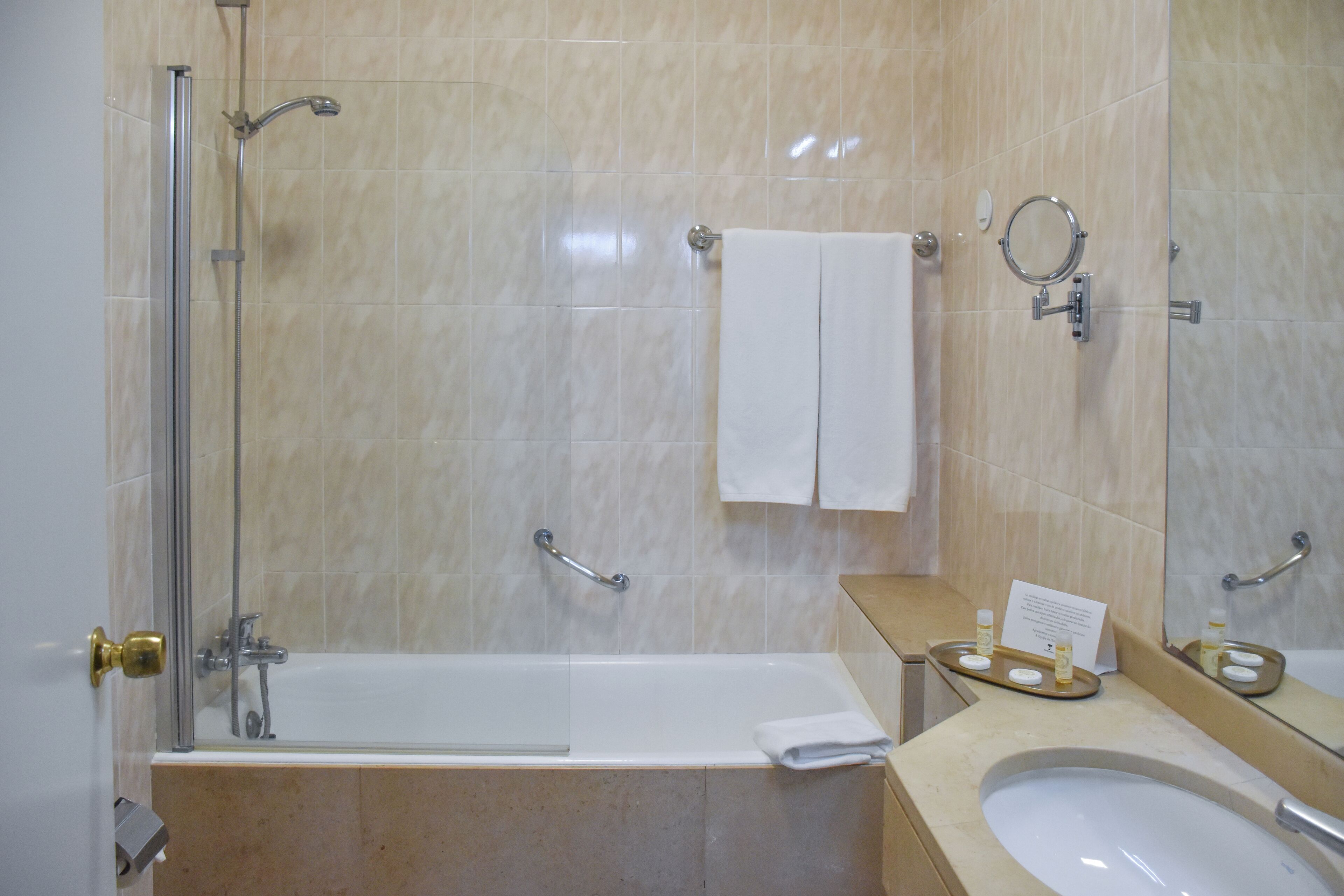 A bathroom with a bathtub, a sink, a mirror, and a towel rack.