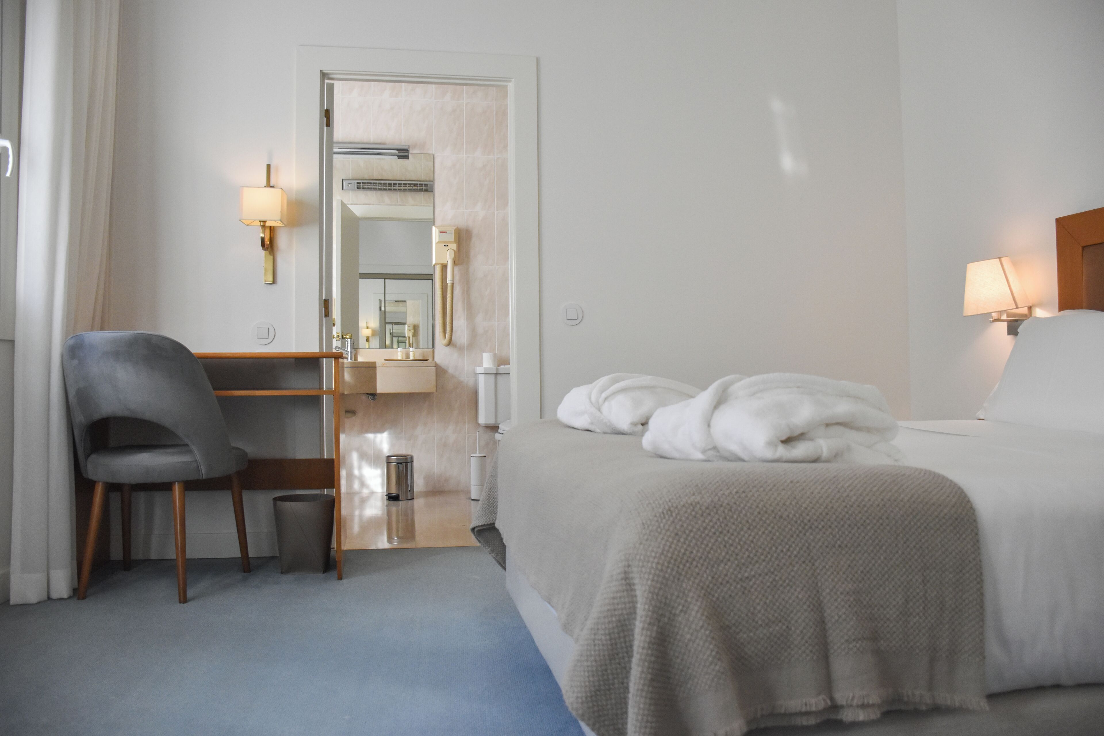 Une chambre d’hôtel comprenant un lit, un bureau, une chaise, un miroir et une lampe.