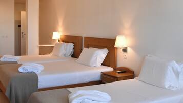 A hotel room with two beds, each with a lamp and a folded towel.