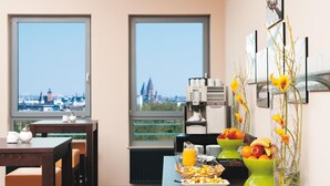 Desayuno con vistas a la ciudad, que incluye una mesa con platos de comida, un frutero y una cafetera.
