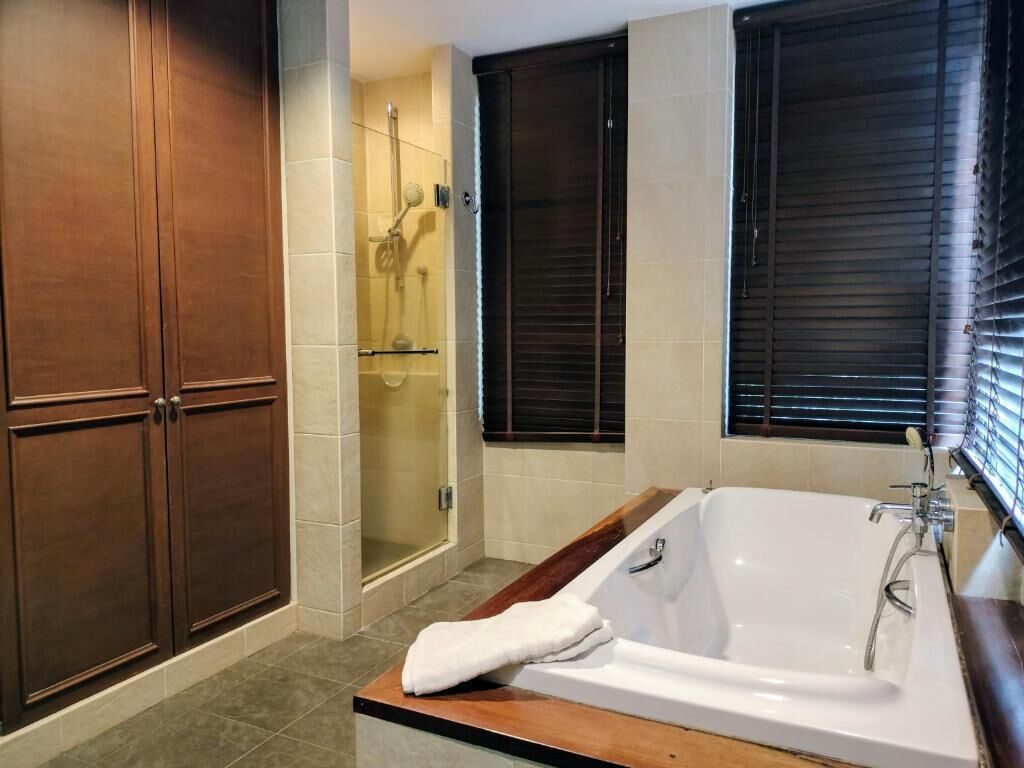 Un baño con bañera, ducha y armarios de madera.
