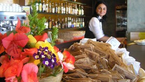 A bar area with a variety of bottles on shelves, a pile of paper currency, and a display of colorful flowers. - TH Costa Rei - Free Beach Club (Muravera)