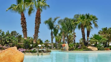 Ein klares Schwimmbecken, umgeben von Palmen und tropischer Vegetation.