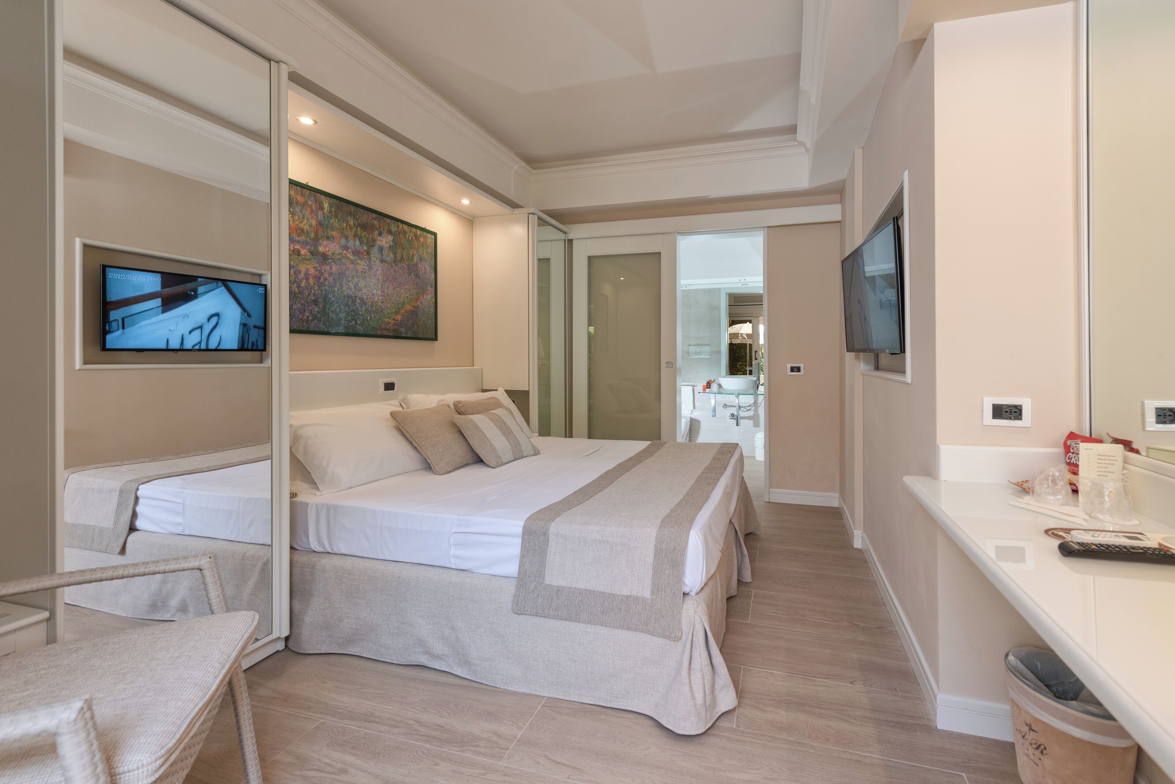 Ein modernes Hotelzimmer mit einem großen Bett, einem Fernseher und einem Schreibtisch mit einem Computer.