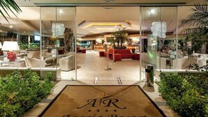A hotel lobby with a reception desk, seating area, and a glass entrance. - Acacia Resort (Campofelice di Roccella)