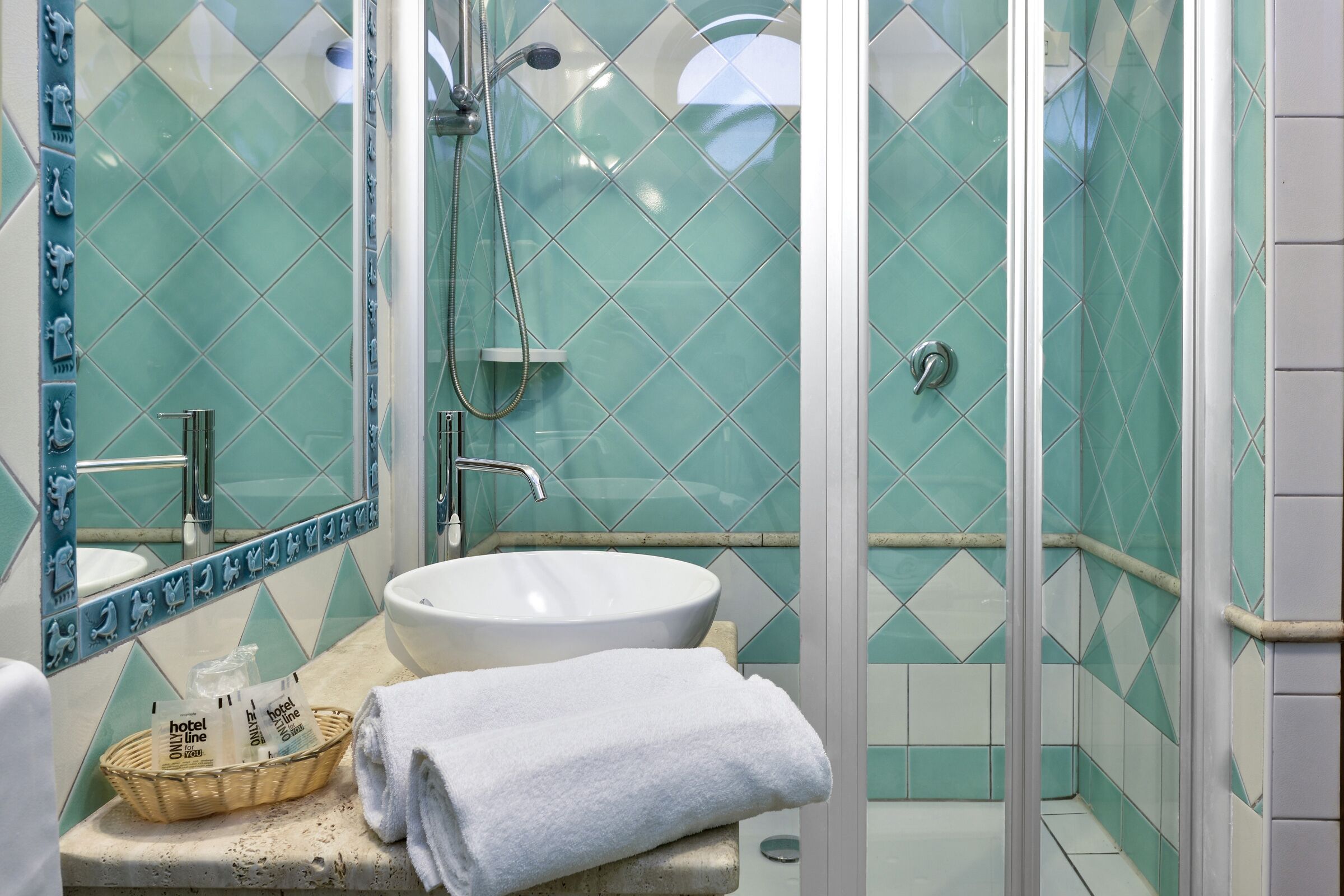 Un bagno con un lavandino bianco, un box doccia in vetro e uno specchio con cornice decorativa.