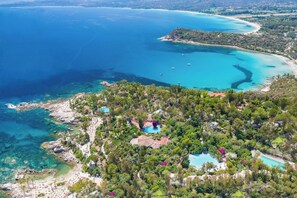 An aerial view of a coastal property with a swimming pool, beach, and lush greenery. - Arbatax Park Resort - Telis by Falkensteiner (Tortoli)