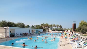 Una piscina con diverse corsie, lettini prendisole e una torretta per il bagnino.