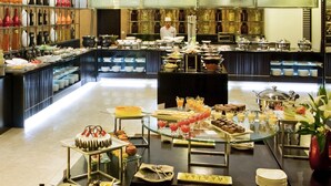 A buffet setup with various food items and a chef in the background.
