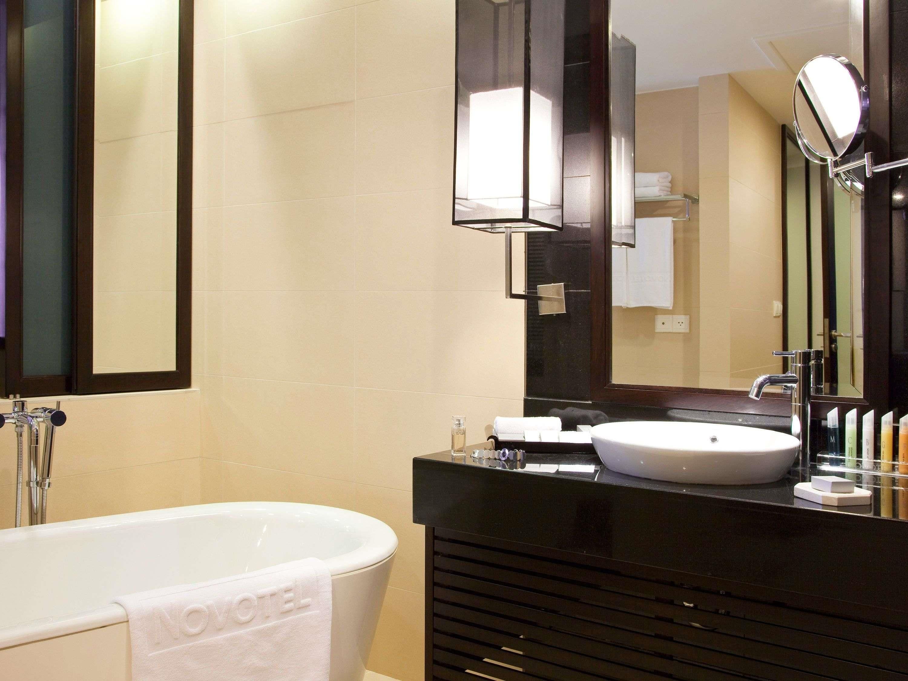 A modern bathroom with a bathtub, a sink, and a large mirror.
