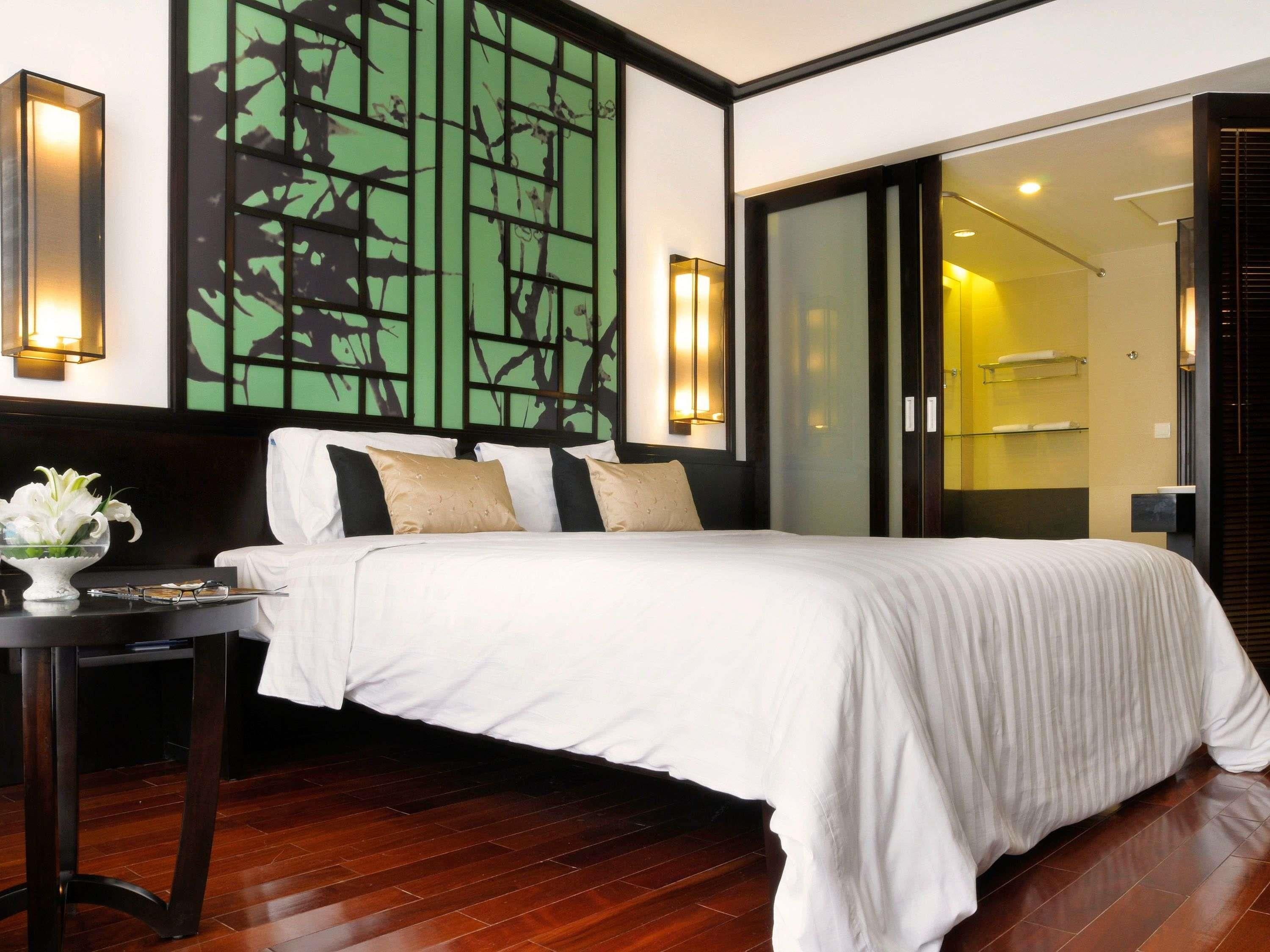 A hotel room with a bed, bedside table, and a wall with a geometric pattern.