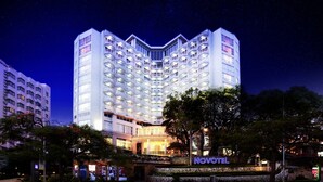 A multi-story hotel with a central atrium, balconies, and a sign reading "NOVOTEL".