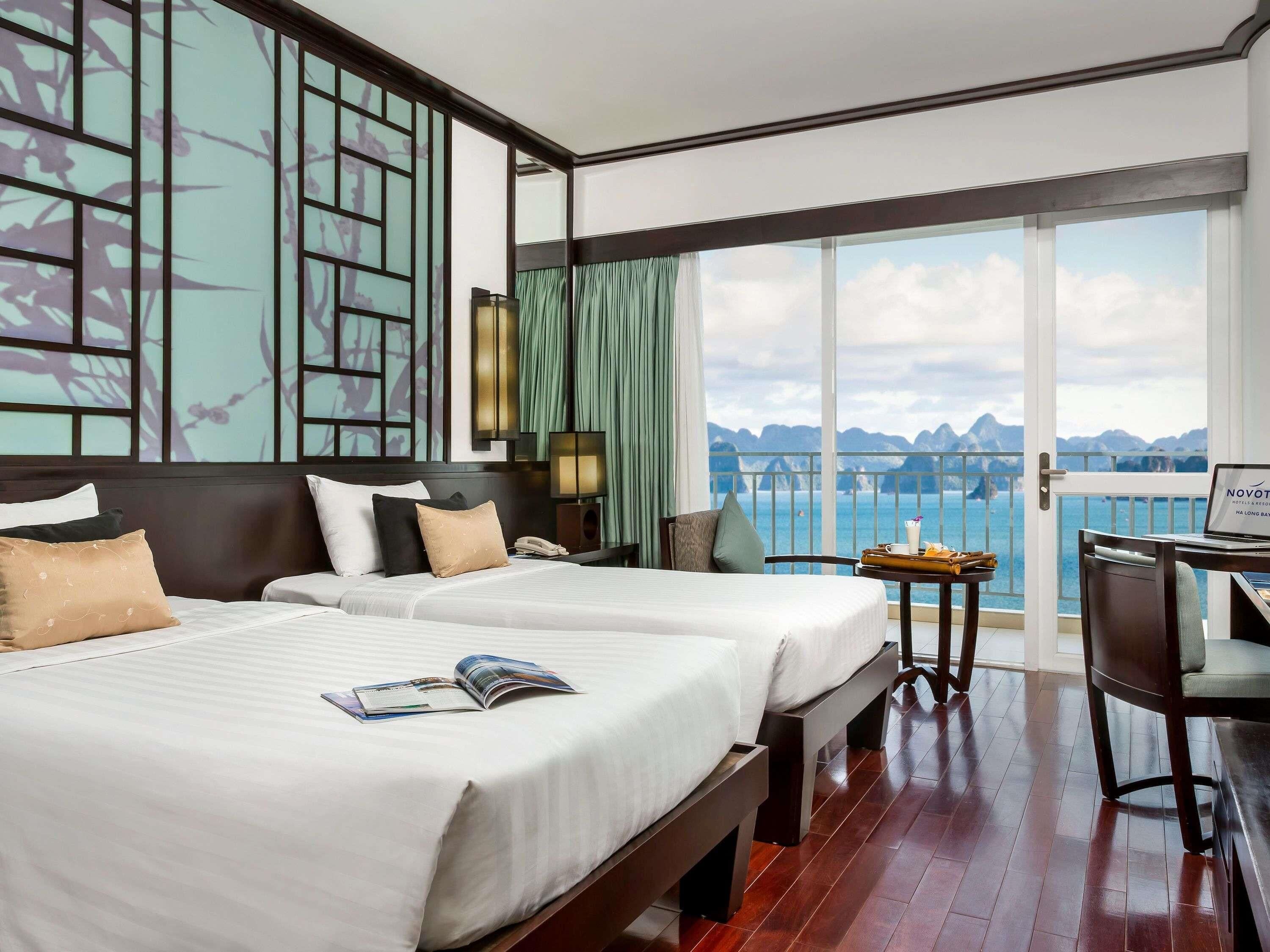 Habitación de hotel con dos camas, un escritorio, una silla, una computadora portátil y vistas al mar.