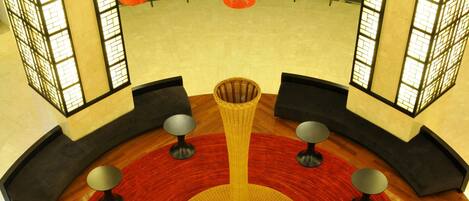 A circular seating area with a central table, surrounded by small round tables, and a red carpet.
