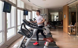 Een sportschool met loopbanden, trainingsapparatuur en grote ramen.