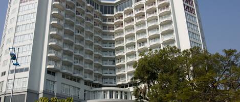 A multi-story hotel with a curved facade, numerous balconies, and a central entrance area.