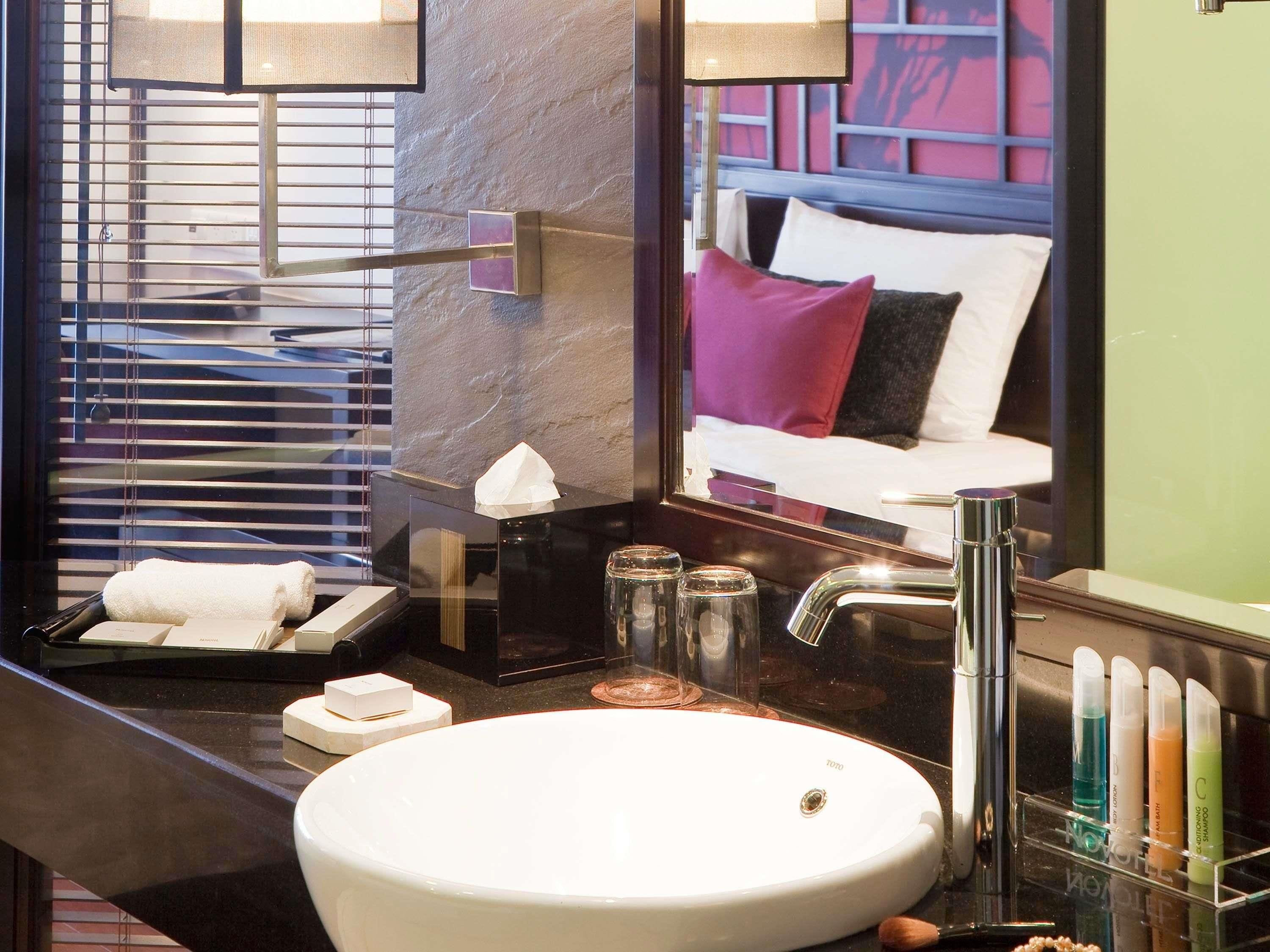 A modern bathroom with a round sink, a mirror, and a vanity with toiletries.