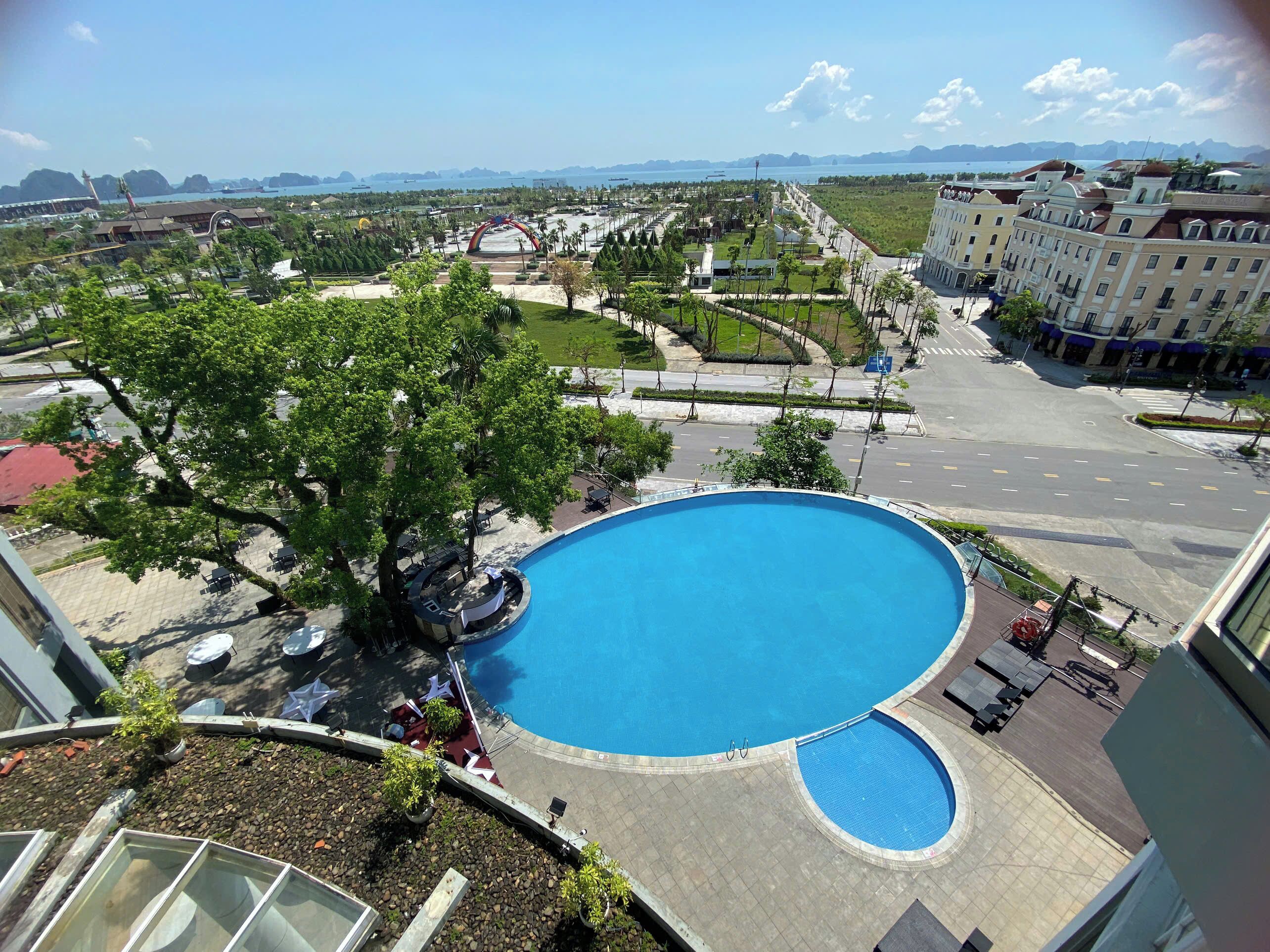 A large swimming pool with a curved design, surrounded by a landscaped area with trees and seating.