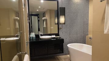 A modern bathroom with a large mirror, two sinks, a bathtub, and a shower area.