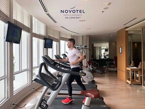 A gym with treadmills, exercise equipment, and large windows. - Novotel Ha Long Bay, (Ha Long)