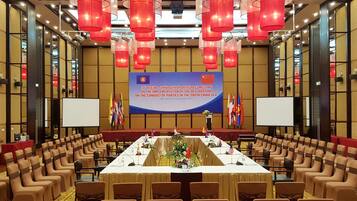 A conference room with a long table, chairs, flags, and a banner.