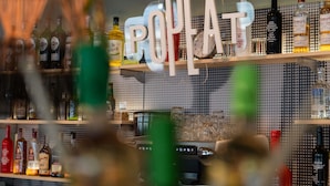Un bar con un letrero que dice 'POPAT' y estantes llenos de diferentes botellas de licor.