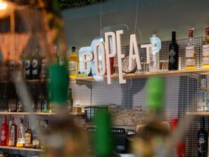 A bar with a sign that reads 'POPAT' and shelves stocked with various liquor bottles. - Hotel ibis Madrid Alcobendas (Alcobendas)