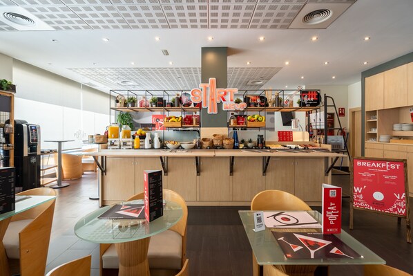 Una cafetería moderna con un mostrador central, mesas de vidrio y sillas de madera.