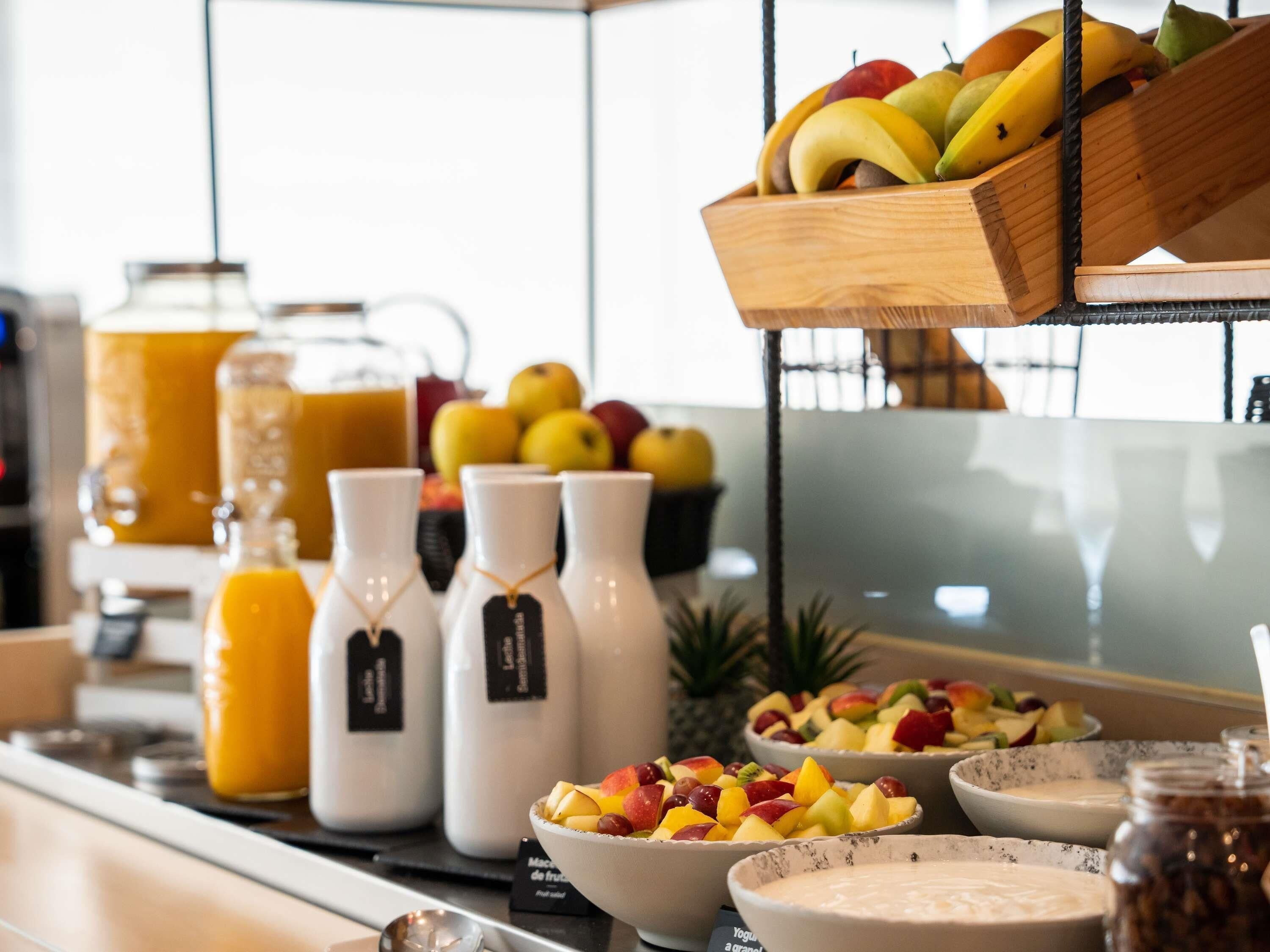 Un bufé de desayuno con fruta, yogur y jugo.