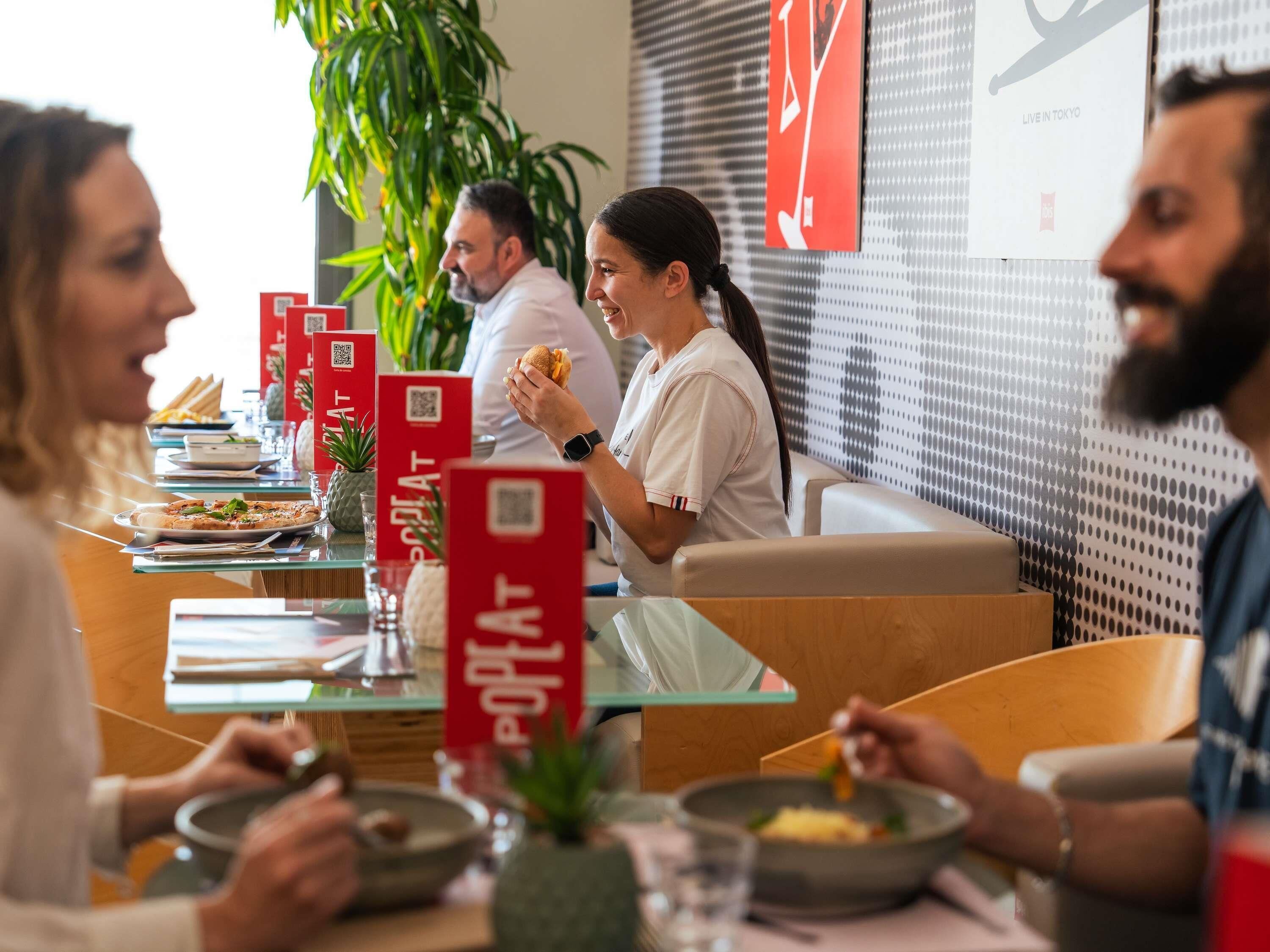 Un restaurante con mesas, sillas y señalización roja.
