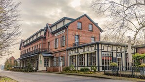 A two-story building with a cafe and restaurant on the ground floor, featuring large windows and a brick facade. - Hotel Bentheimer Hof (Bad Bentheim)