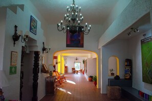 A spacious hallway with a chandelier, framed pictures, and a map on the wall. - Villas Arqueologicas Teotihuacan (Teotihuacan)